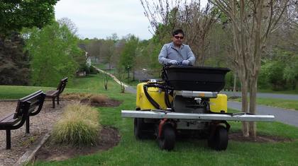 Crew member applying fertilizer with a broadcast spreader in Maryland
