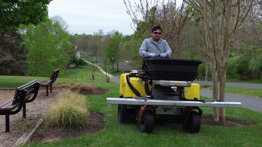 Crew member applying fertilizer with a broadcast spreader in Maryland